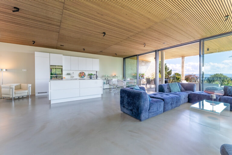 Blick aus der Kaminecke in den Wohnbereich mit offener Küche und großer Terrasse