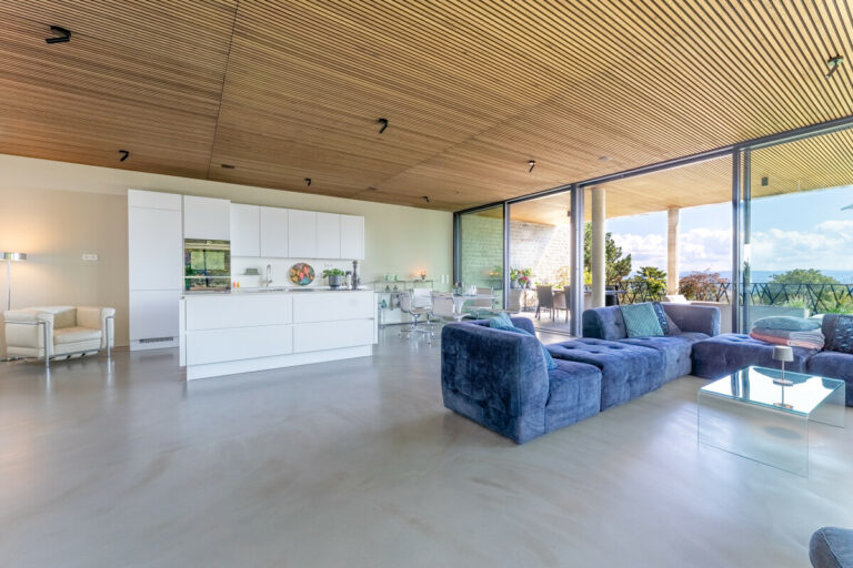 Blick aus der Kaminecke in den Wohnbereich mit offener Küche und großer Terrasse